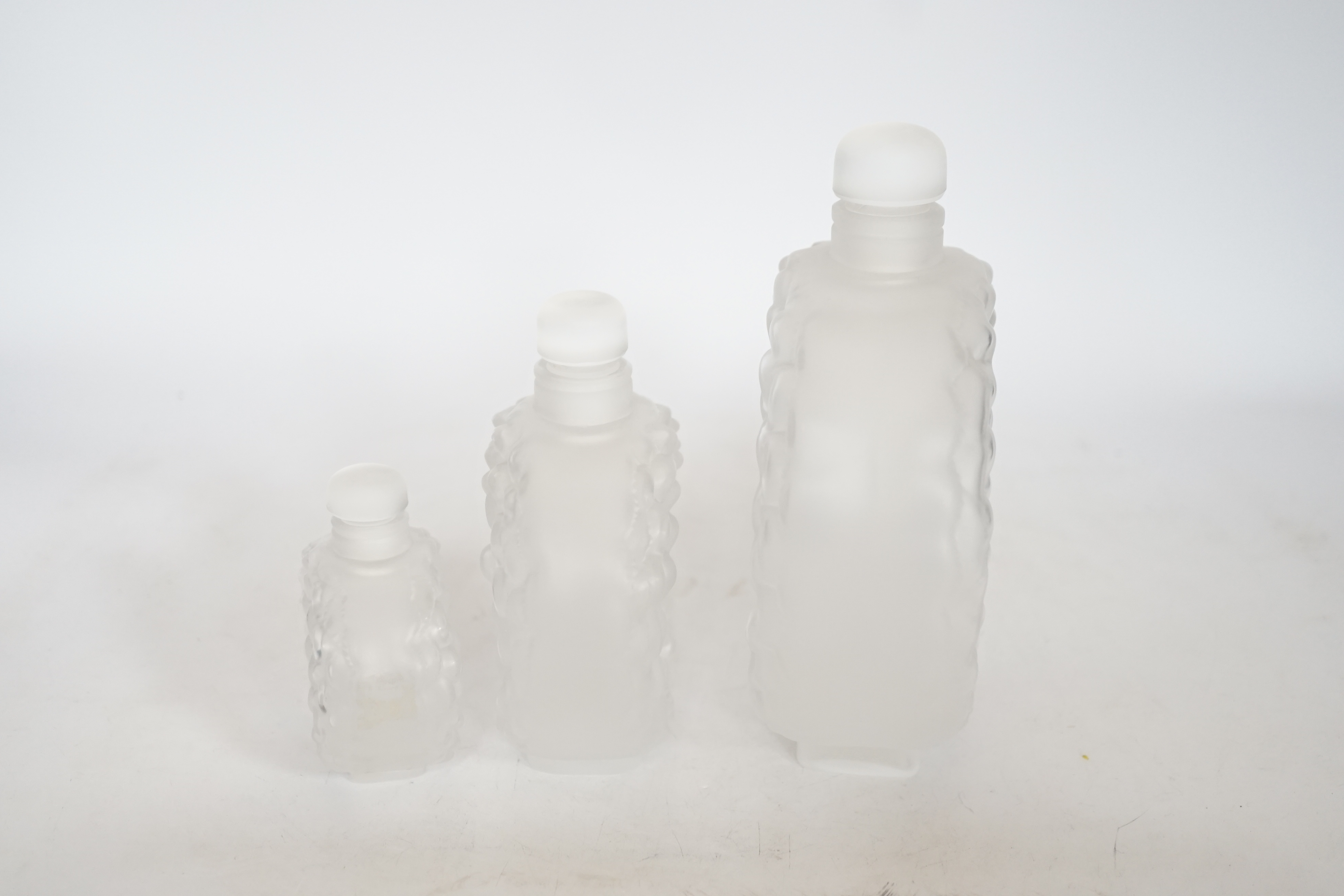 Three graduated Lalique Dahlia pattern glass scent bottles and stoppers, signed to the bases, largest 18cm high